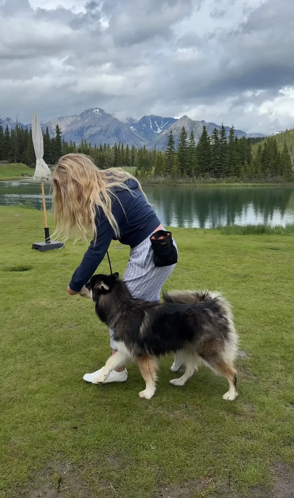 Kaitlin playing with a fluffy dog beside a mountain lake