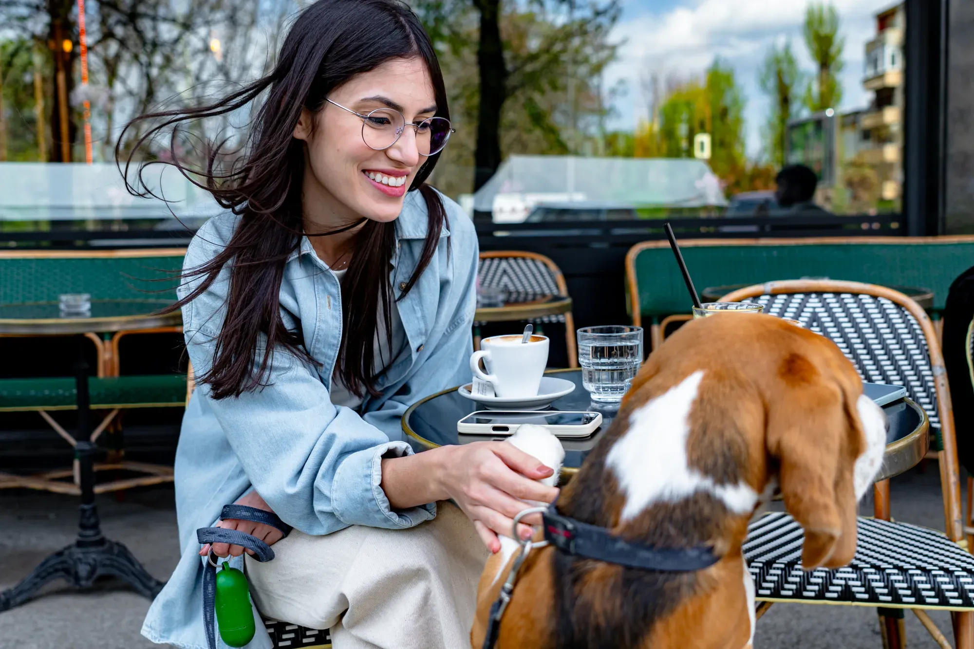 Calm dog settled beside its owner's table on a busy cafe patio