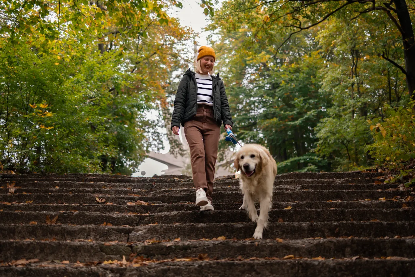 Woman walking down park stairs with a golden retriever on a loose leash